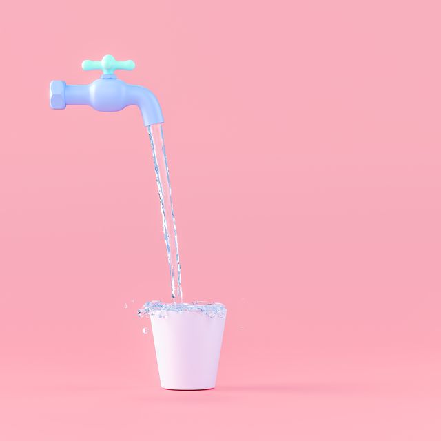water falling in bucket from tap against pink background