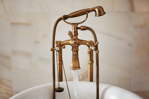 water running down from antique bronze faucet tap into the bathtub