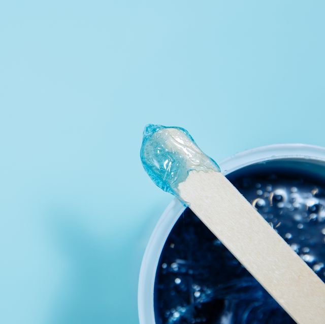 waxing labia, effects of waxing pubic hair blue soft wax lies on a depilation spatula sharpness is on wax with a spatula a wooden spatula lies on a jar of wax a can of wax is located in the lower right corner background image is blue