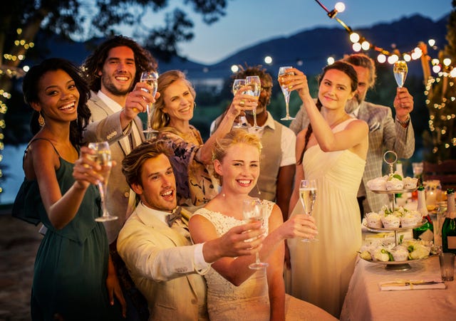 a bride and groom and wedding guests toasting champagne