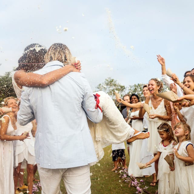 invités au mariage jetant du riz aux jeunes mariés, à l'extérieur