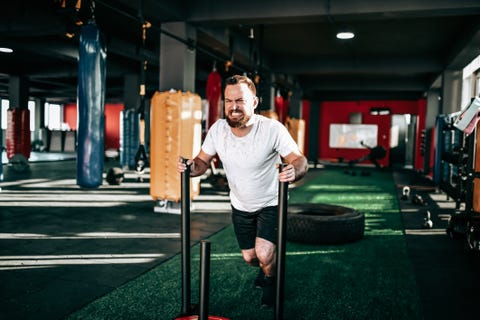 Weight cart cross training by tough male athletes in the gym