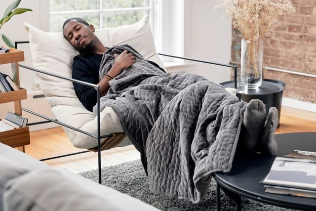man sleeping on a chair with a weighted blanket