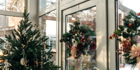 welcome home christmas tree window with decorated glowing christmas tree inside a house and bright outdoor decorations, night scene, light blur christmas and new year holidays background