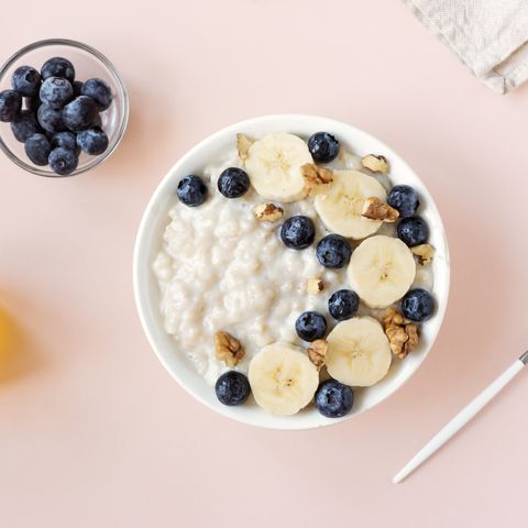 what to eat during periods for energy oatmeal porridge with walnuts, blueberries and banana in bowl on pink   healthy organic breakfast, oats with fruits, honey and nuts