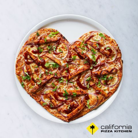 california pizza kitchen pizza with chicken, bbq sauce, and red onions on white granite background