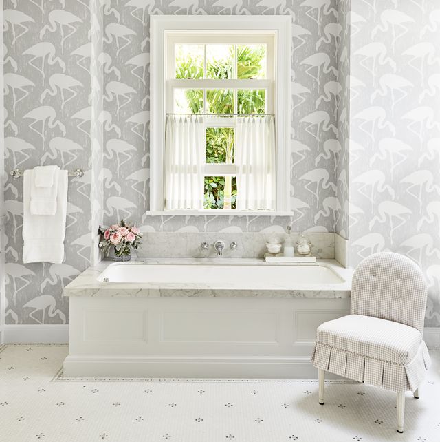 fun flamingo wallpaper in subtle gray and white on the walls around a soaking tub in a white bathroom