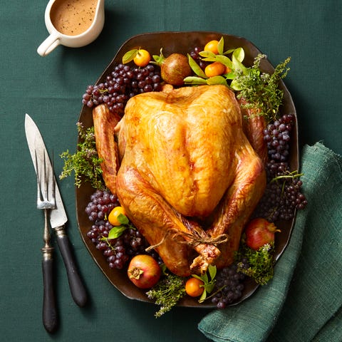 whole roast turkey on platter with garnishes and green tablecoth whole roast turkey on platter with garnishes and green tablecoth