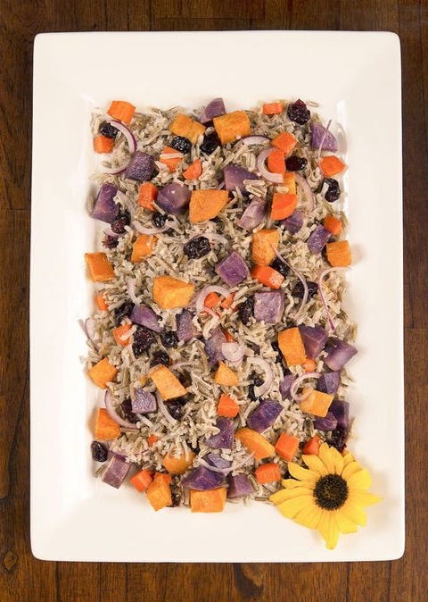 white platter full of wild rice and roasted root vegetables on a brown wood background