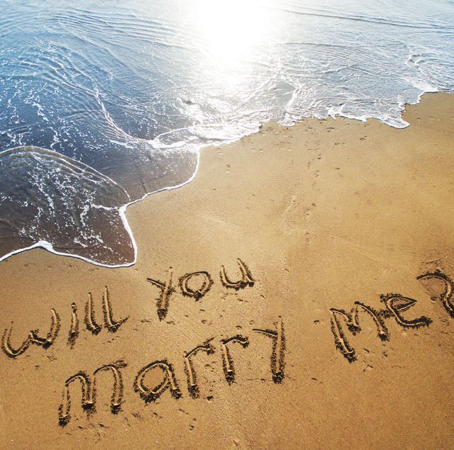 Will you marry me written in sand on beach