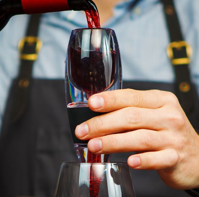 man in apron pouring red wine through an aerator