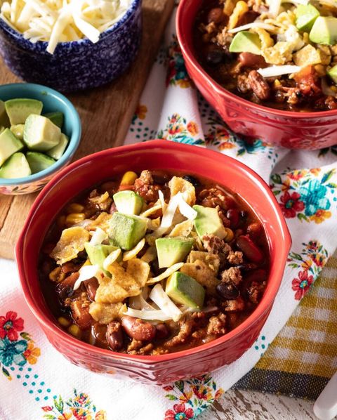 slow cooker turkey chili in red bowls with avocado