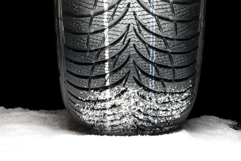close up of a tire on snow with flakes of snow in the treads