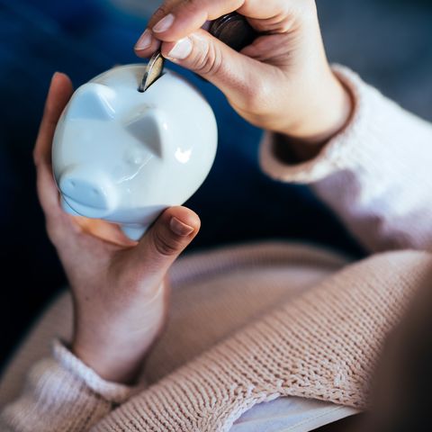 Woman adding a coin to savings in a piggy bank.