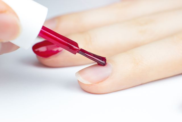 woman applies red nail polish