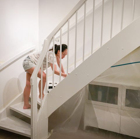 Mujer aplicando pintura blanca fresca a las escaleras Mujer aplicando pintura blanca fresca a las escaleras.