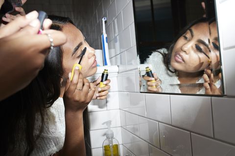 mujer aplicando rímel mientras mira el espejo