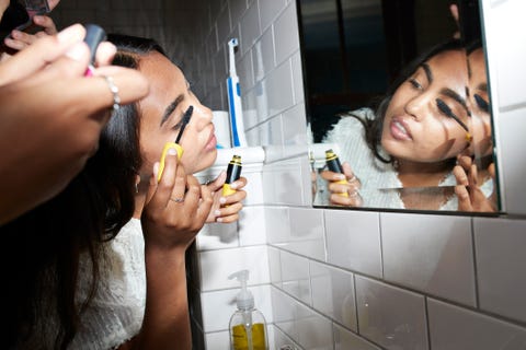 Mujer aplicando rímel mientras mira el espejo mujer aplicando rímel mientras mira el espejo