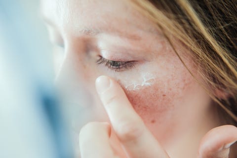 Woman applying skin face cream.