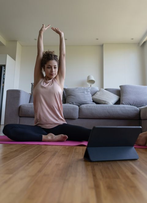 woman at home following an online yoga class on her tablet