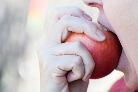 Woman biting fresh red apple