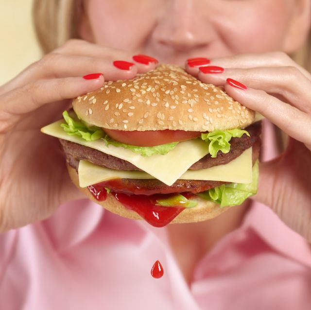 woman biting into hamburger with ketchup drip