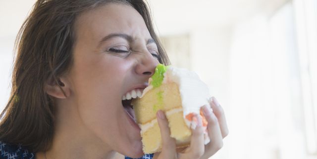 woman biting piece of cake
