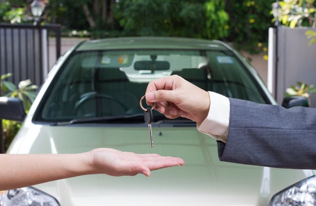 woman buying a car and salesman handling keys