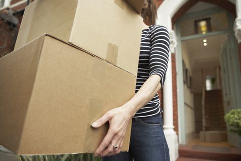 Woman carrying brown boxes from house