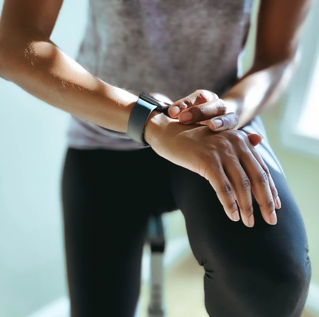 woman checks her fitness stats on smart watch after indoor cycling workout