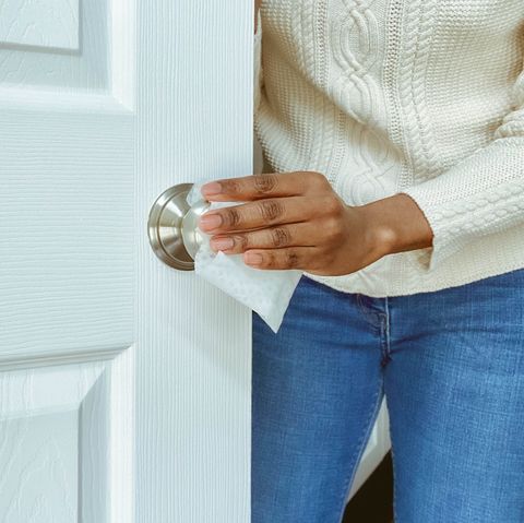 Woman Cleans Interior Doorknob Using Disinfectant Wipe