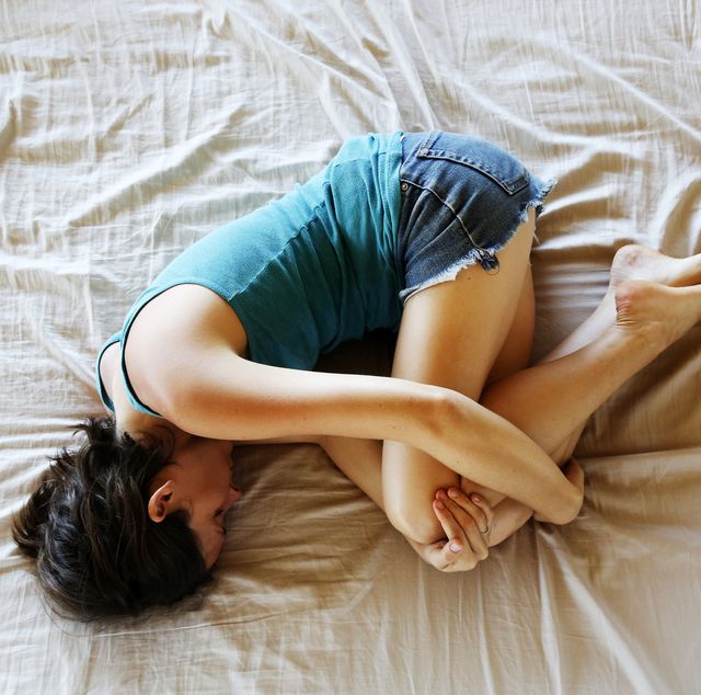 woman curled in fetal position on bed