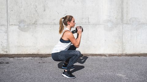Woman doing squats with a kettlebell