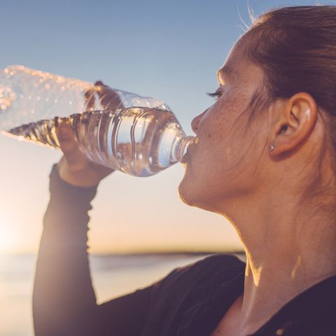 Woman drinking water seaside.