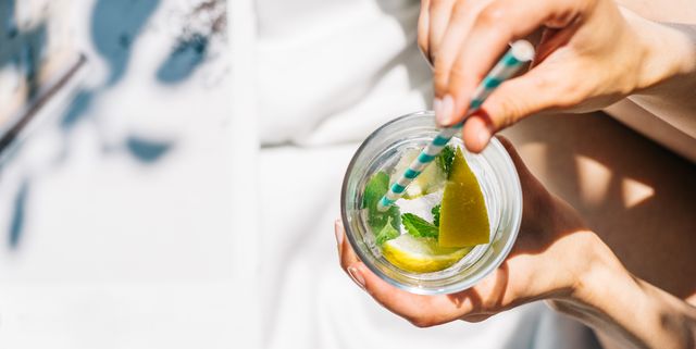 woman drinking water with fresh lemon, lime and mint