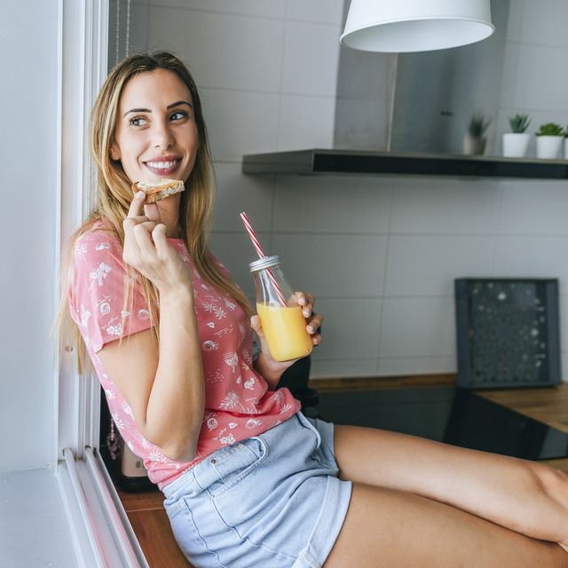 woman eating toast and drinking orange juice