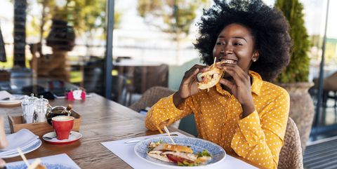 woman enjoying eating sandwich at restaurant