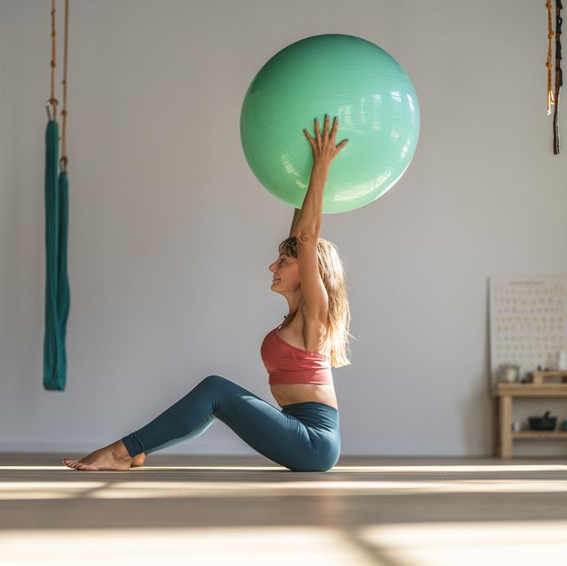 woman exercising with fitness ball sitting in yoga studio
