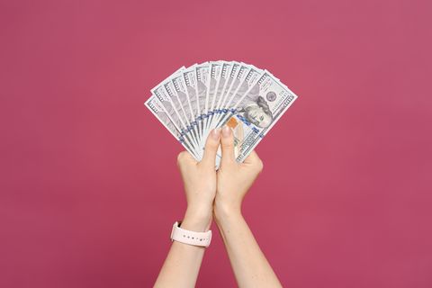 woman hand holding money dollars on pink background