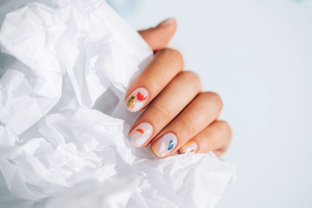 woman hand with beautiful colorful manicure is holding white paper trendy bright colors of the year