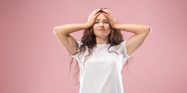 woman having headache isolated over pink background