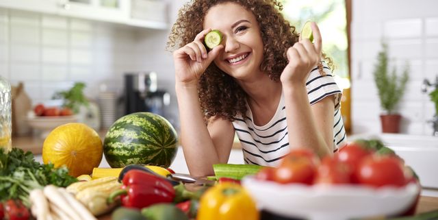 woman holding a slice of cucumber