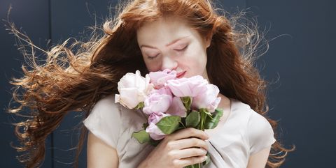 Woman holding and smelling bunch of roses