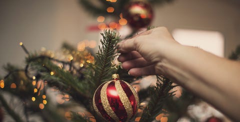 Woman holding Christmas bauble in front of illuminated Christmas tree woman holding christmas bauble in front of illuminated christmas tree