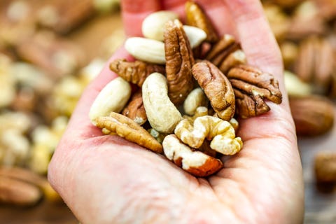 Woman holding handful of fresh nuts. Mixed whole nuts. Nut Sources of Vitamin B9 Folate