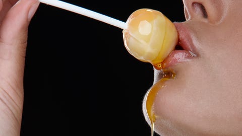 Woman holding honey lollipop to her lips