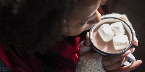 Woman holding mug with hot chocolate and marshmallows