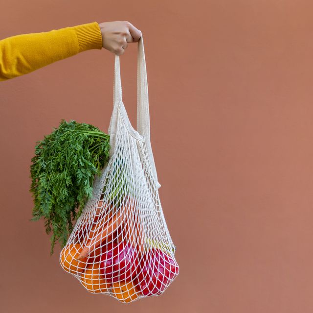 woman holding reusable cotton mesh bag with fruit and vegetables