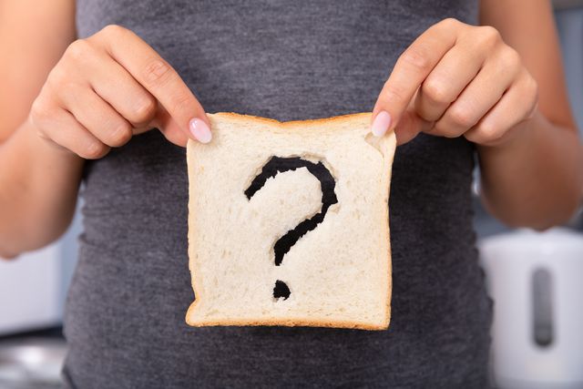woman holding slice of bread with question mark sign