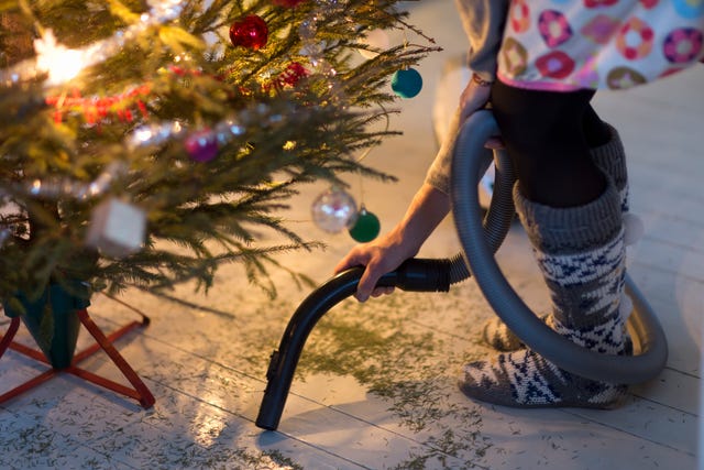 woman hovering needles under christmas tree